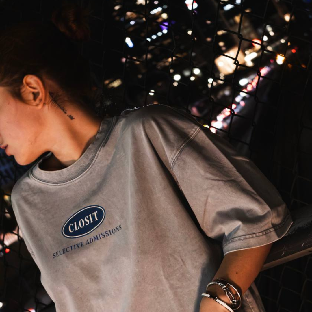 Front view of a woman wearing the light gray Closit tee with Selective Admissions chest logo.